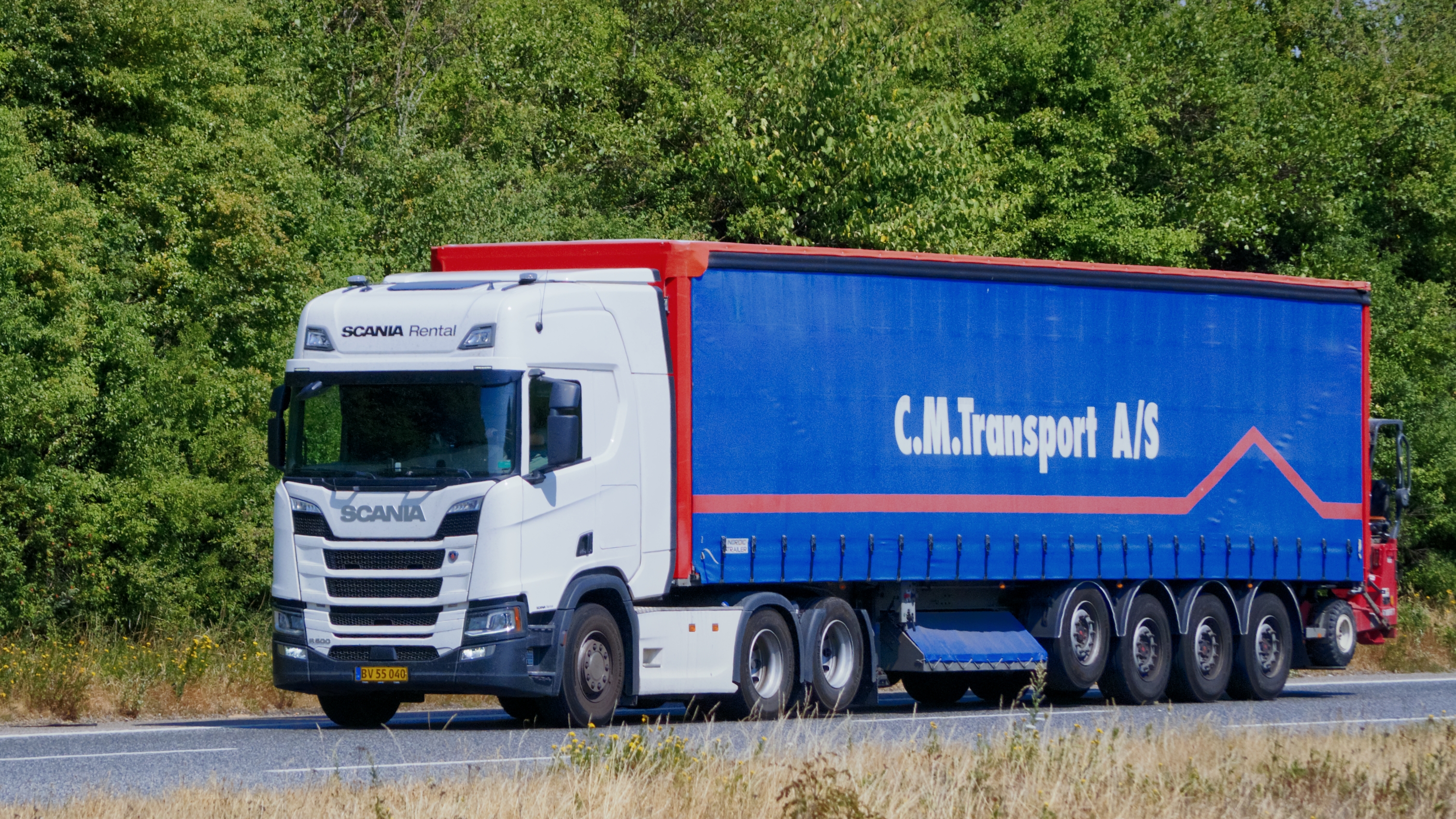 หัวลาก Scania สีขาวพร้อมหางผ้าใบบนถนน